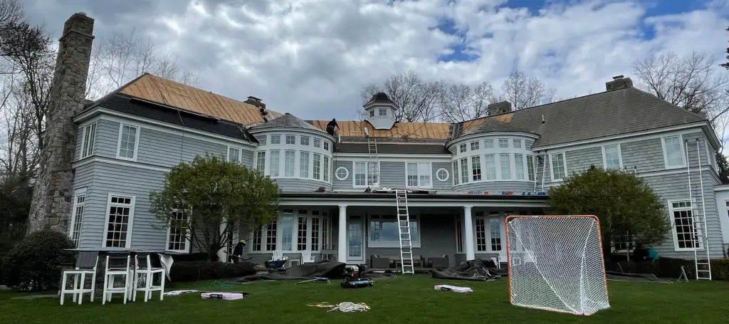 House undergoing roof renovation with workers and equipment visible.